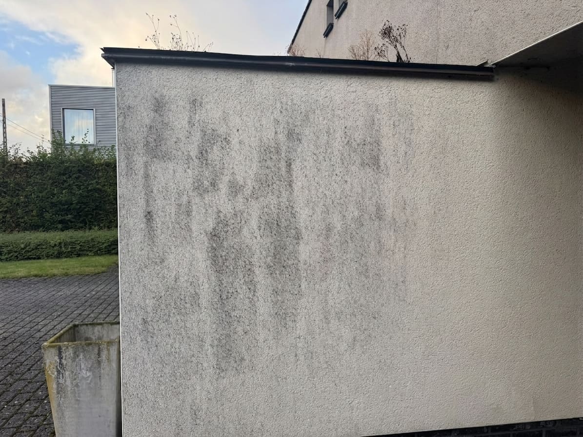 Crepi-gevel met donkergrijze atmosferische vervuiling en vuilstrepen