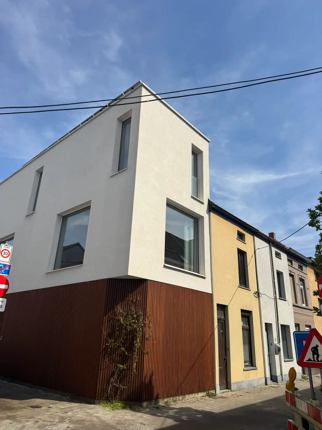 Verzorgde witte crepi-hoekwoning met onderbouw in houtlook.