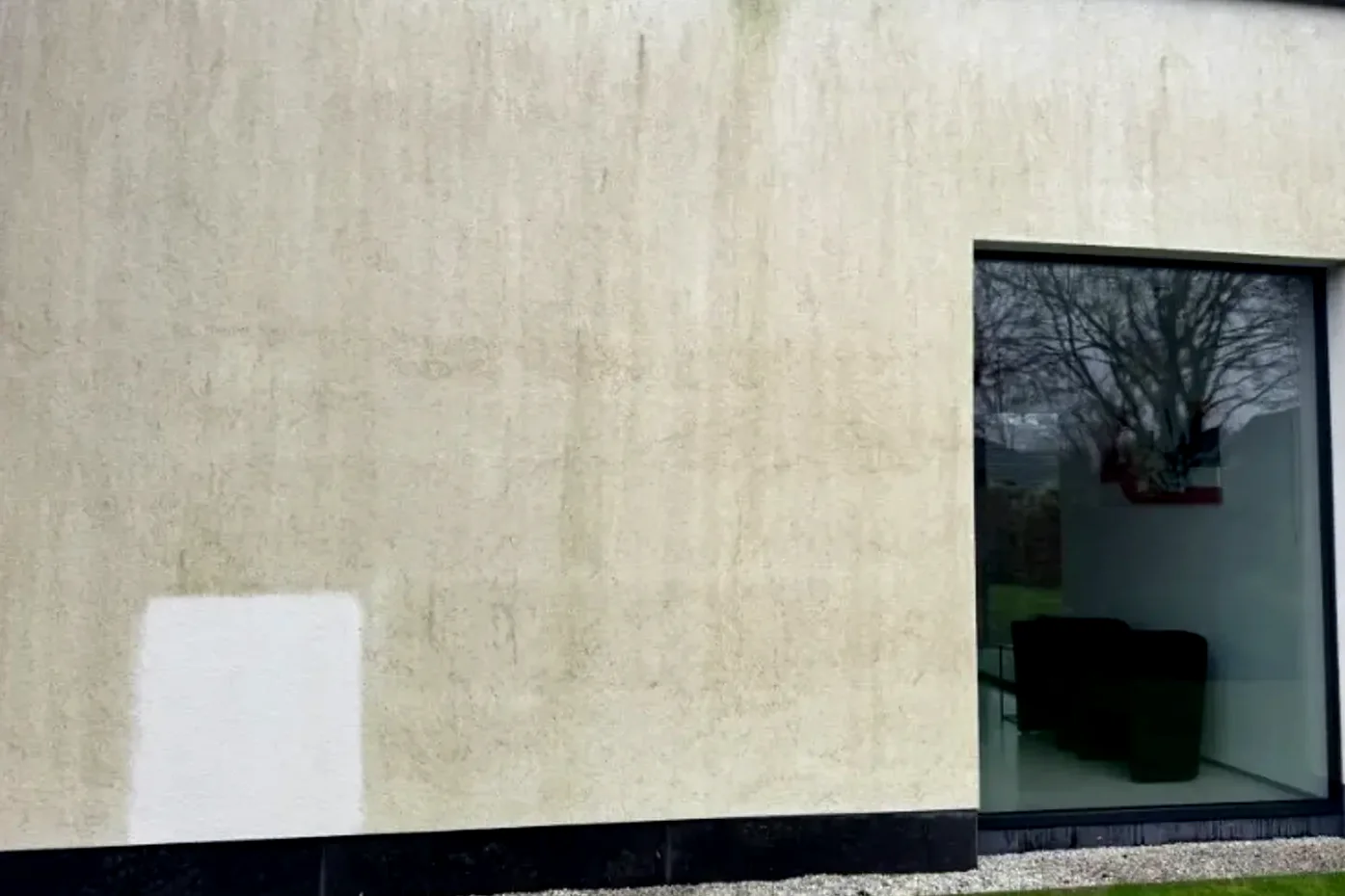Crepigevel met groene aanslag en een wit proefvlak waar MOS Reinigingsservice al gereinigd heeft.