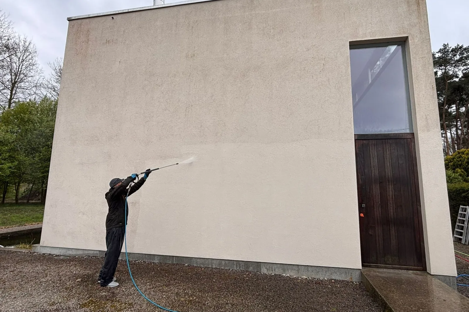 Een medewerker van MOS spoelt een crepigevel af tijdens een reiniging in Destelbergen.