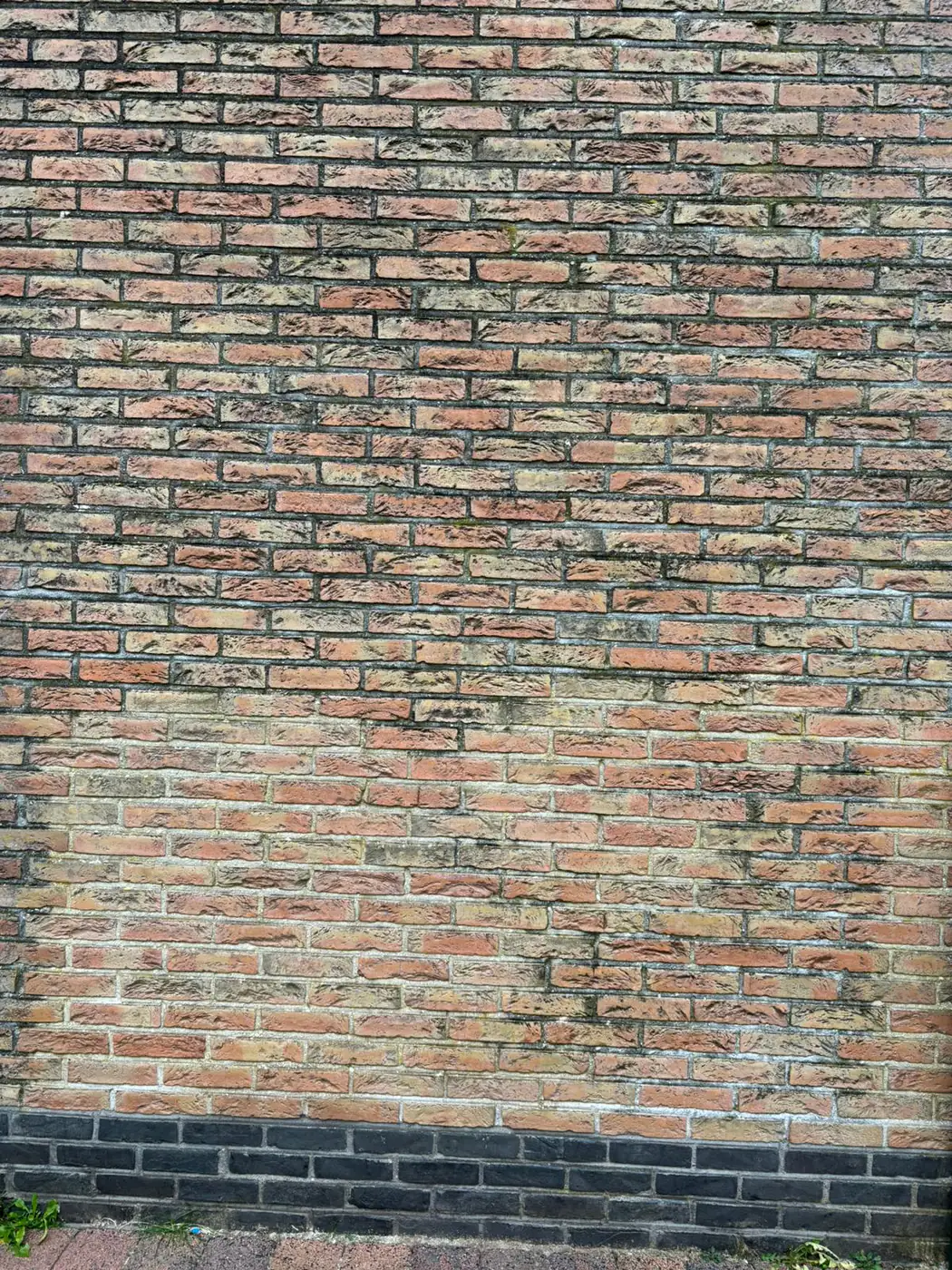 Bakstenen gevel met donkere aanslag op de steen en in het voegwerk.