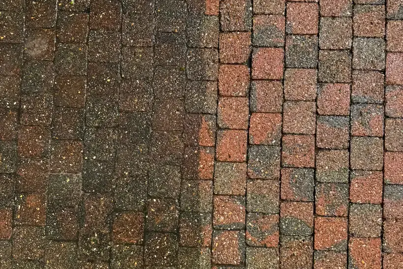 Rode klinkers waarvan de linkerhelft nog donker en vuil is en de rechterhelft gereinigd, met de rode kleur terug zichtbaar.