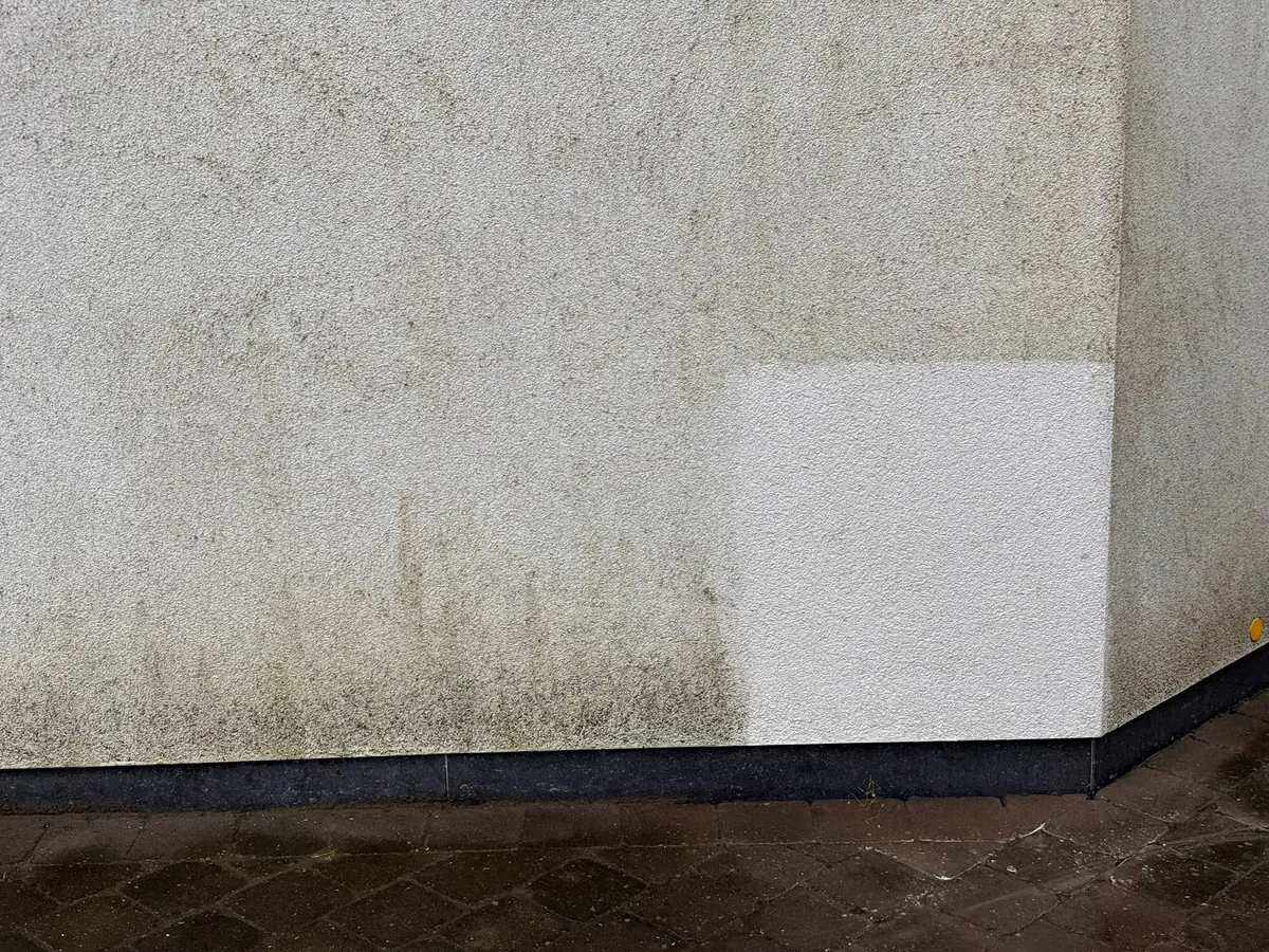 Grauwe crepigevel waarop onderaan een klein vierkant al gereinigd is.