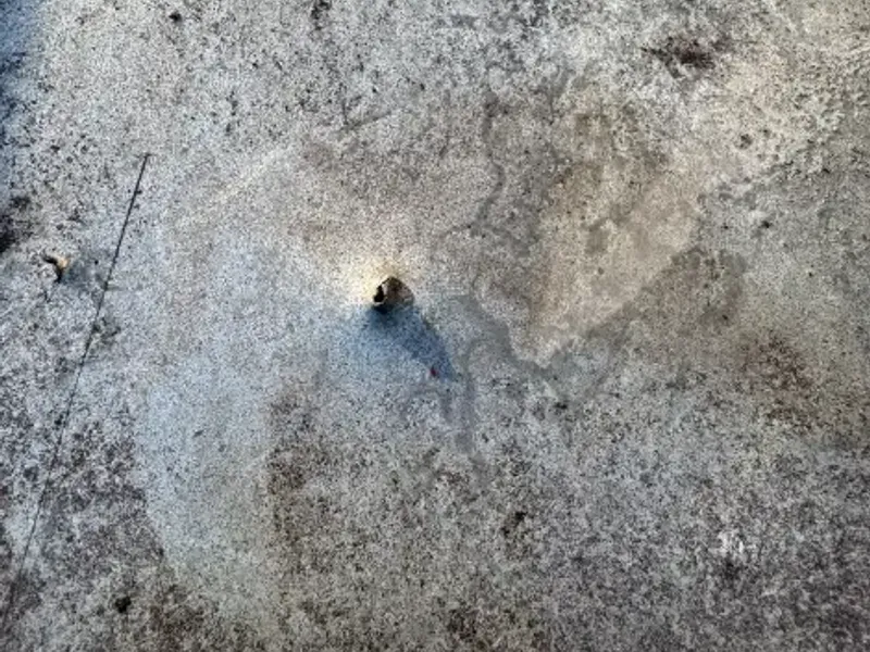 Close-up van het zinkwerk van de dakgoot waarin een klein gaatje zichtbaar is.