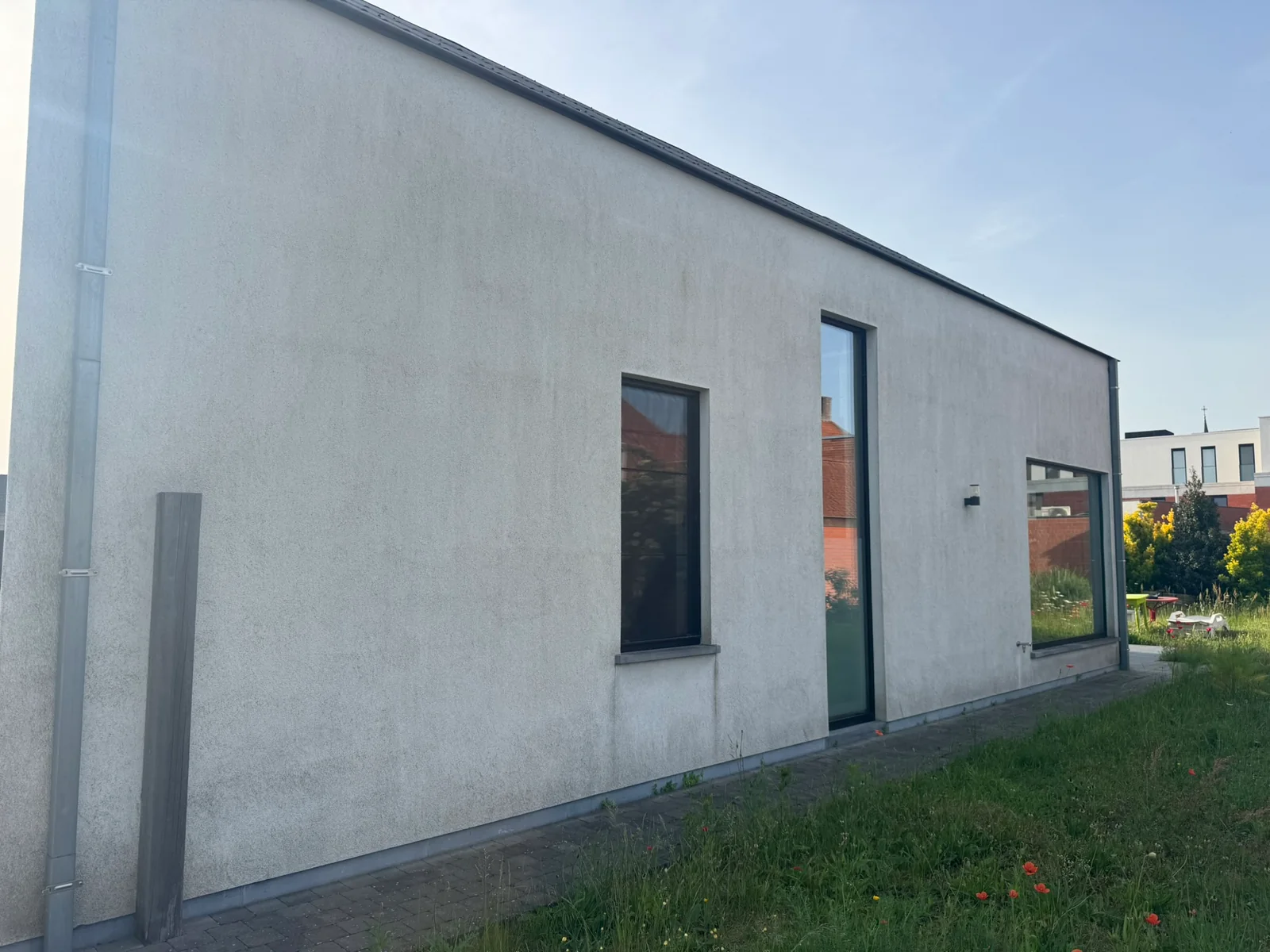 Crepi reinigen — grauwe, vlekkerige gevel vóór behandeling in Eeklo.