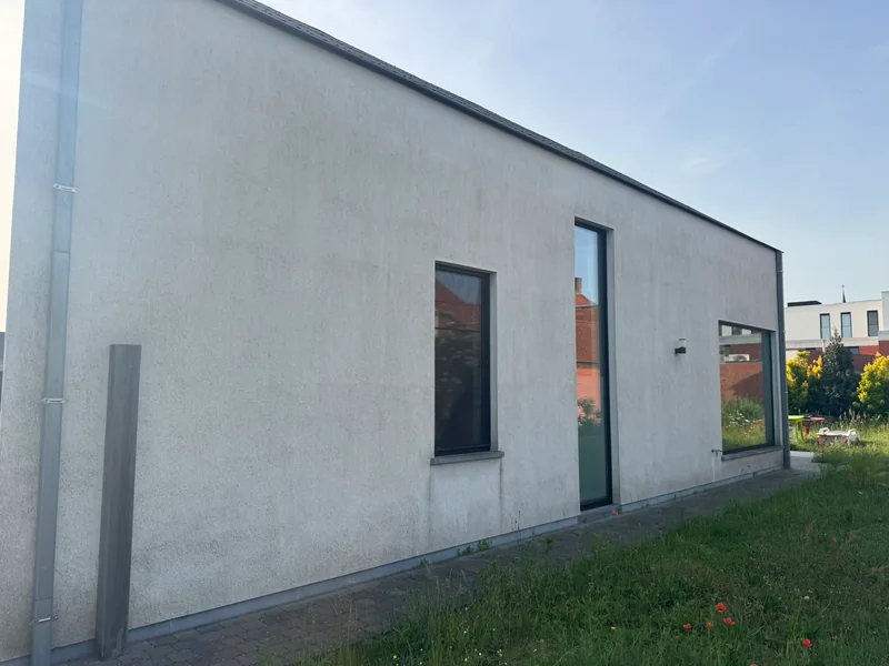 Crepi reinigen — grauwe, vlekkerige gevel vóór behandeling in Eeklo.
