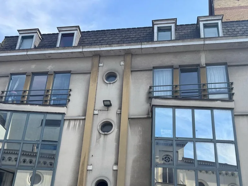 Crepi schilderen — grauwe stadsgevel met donkere regensporen vóór behandeling in Gent.