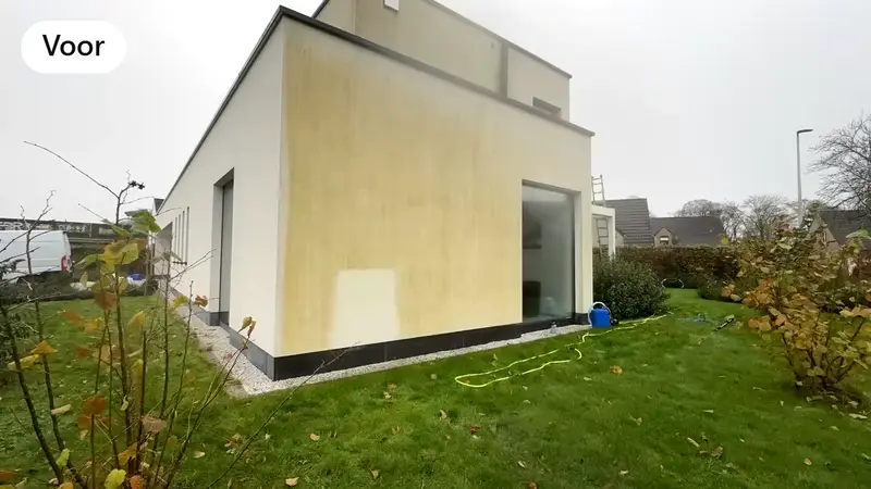 Een witte crepigevel met gele en groene aanslag, vóór de reiniging.