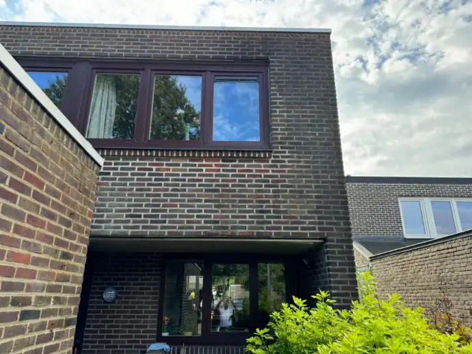 Achtergevel bakstenen woning met mos en aanslag vóór reiniging